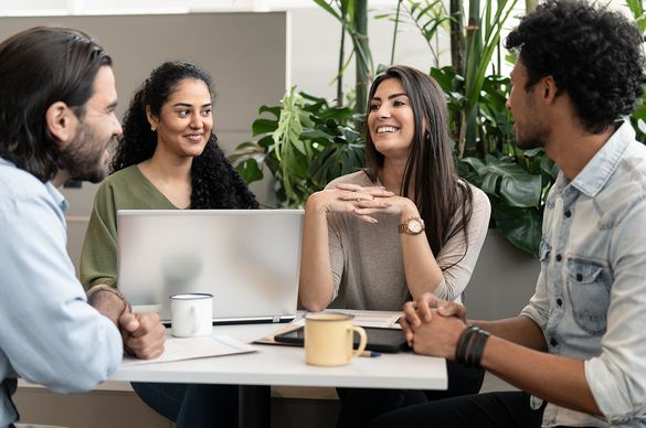 Eine Gruppe von vier Personen sitzt gemeinsam am Tisch und führen ein Gespräch