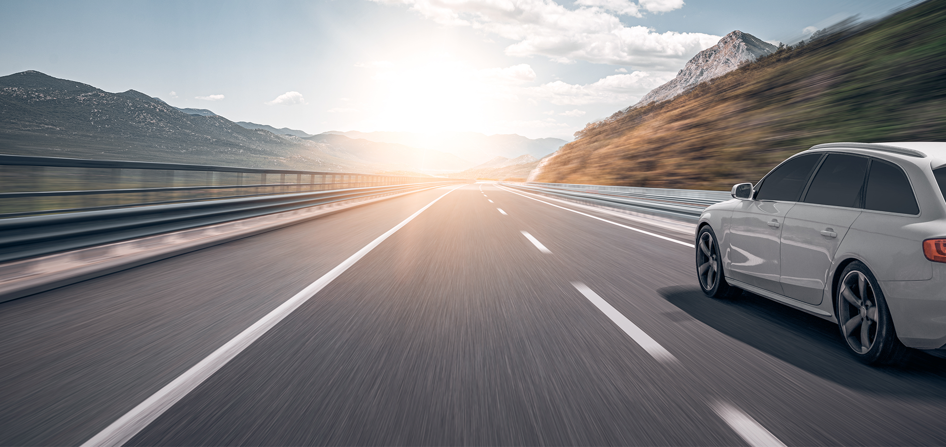 Weißes Auto fährt in Richtung Sonnenuntergang