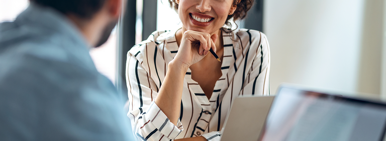 Frau sitzt mit Laptop am Tisch in einem Beratungsgespräch