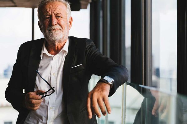 Älterer Mann hält seine Brille in der Hand
