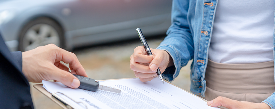 Frau unterschreibt einen Auto Kaufvertrag