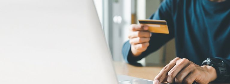 Mann sitzt am Laptop und gibt seine Kreditkartendaten ein