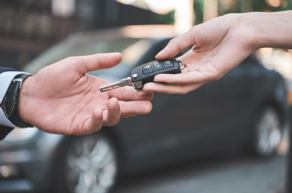 Autoverkäufer übergibt den Autokäufer den Autoschlüssel