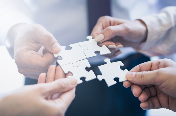 Vier Personen halten je ein Puzzleteil in der Hand