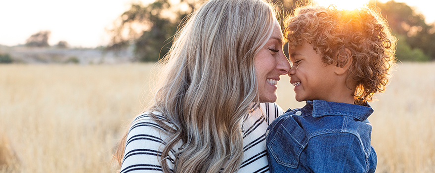 Mutter hält ihren Sohn am Arm und lächelt ihn an