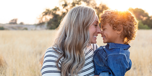 Mutter hält ihren Sohn am Arm und lächelt ihn an