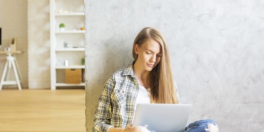 Studentin sitzt mit Laptop in ihrer Wohnung