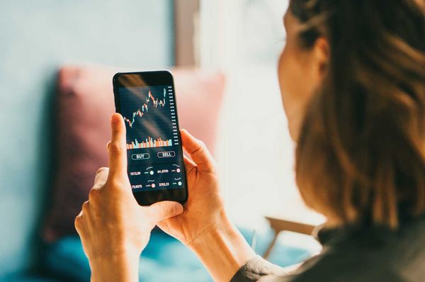 Frau schaut sich am Smartphone Aktienkurse an