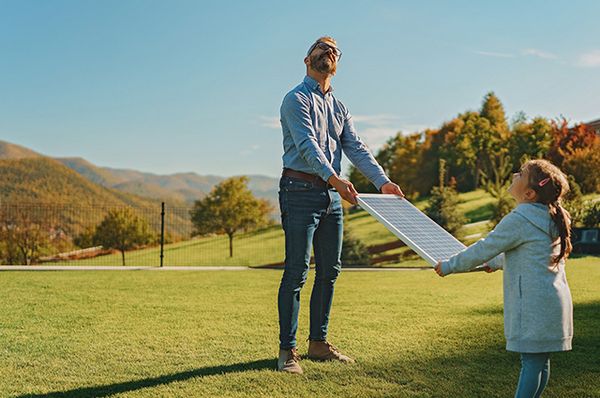 Ein Vater testet mit seiner Tochter ein Solarpanel auf einer Wiese