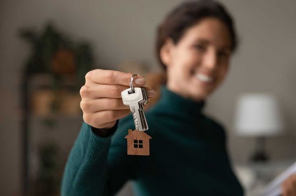 Frau hält Haustürschlüssel mit einem Anhänger