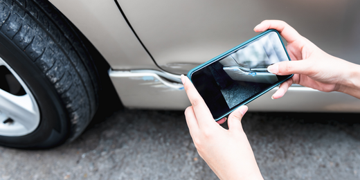 Person fotografiert einen Schaden am Auto mit dem Smartphone Person fotografiert einen Schaden am Auto mit dem Smartphone
