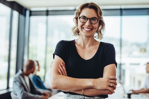 Chefin mit verschränkten Armen und lächelndem Gesicht