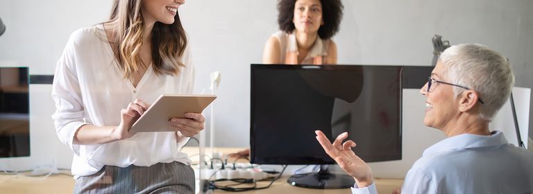 Drei Arbeitskolleginnen führen ein Gespräch am Arbeitsplatz