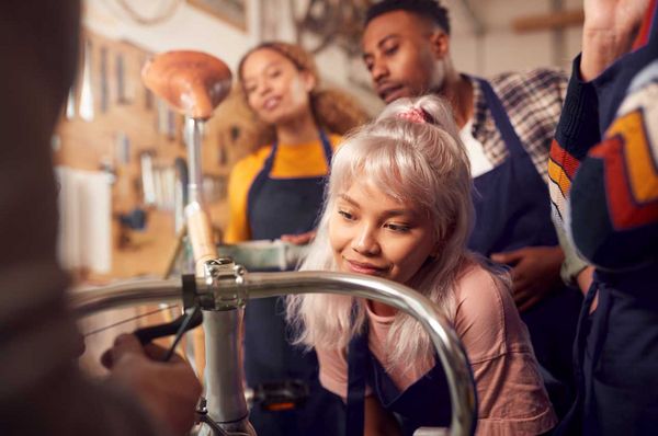 Junge Frau mit blonden Haaren repariert ein Fahrrad