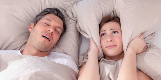 Schnarchschiene Frau und Mann liegen im Bett, da der Mann schnarcht kann Frau nicht schlafen.