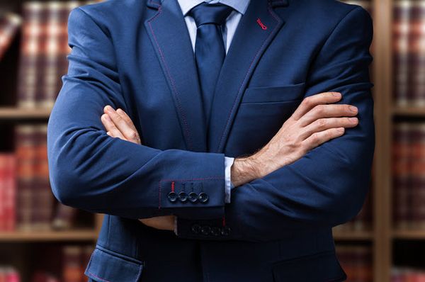 Oberkörper eines Mannes im blauen Anzug mit verschränkten Händen