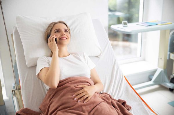 Sonderklasse nach Unfall Versicherung Frau liegt im Einzelzimmer im Krankenhaus und telefoniert