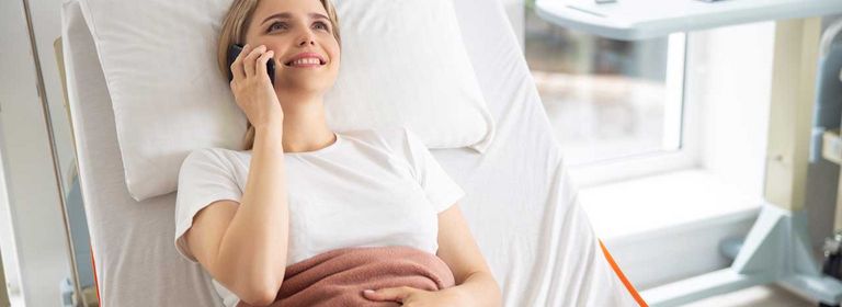 Sonderklasse nach Unfall Versicherung Frau liegt im Einzelzimmer im Krankenhaus und telefoniert