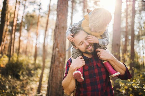 Vater trägt seinen Sohn auf den Schultern im Wald