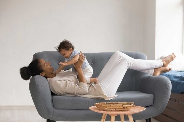 Mutter liegt mit ihrem Baby auf einer Couch