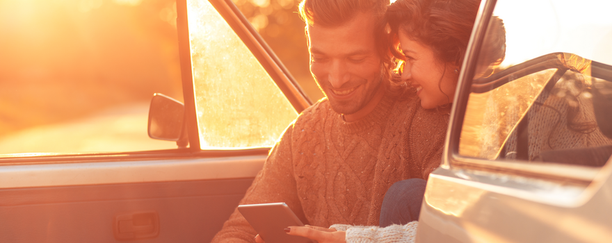 Pärchen sitzt im Auto und berechnet Kosten einer Autoversicherung