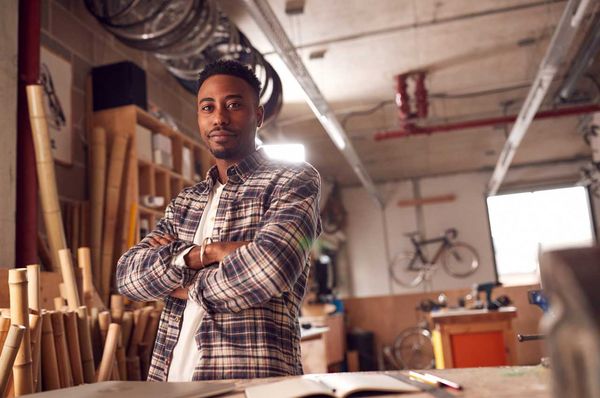 Junger Mann steht mit verschränkten Armen in einer Werkstatt