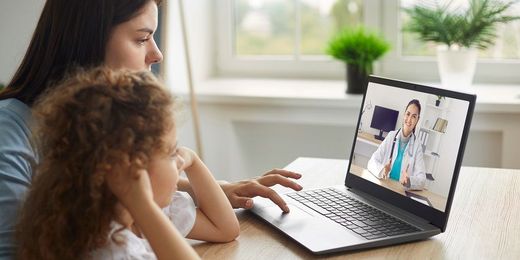 Mutter nutzt mit krankem Kind Telemedizin und telefoniert per Video-Telefonie mit einer Ärztin